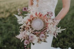 Hochzeitsfloristik boho brautstrauß vintage mit Königs Protea , astible , sterndolde im Hintergrund Bohobrautkleid - florist für freie Hochzeit
