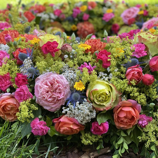 Nahaufnahme Moderner Bunter Trauerkranz ca. 80 cm Durchmesser mit blauen Disteln - Mannstreu, Farbige Freiland Rosen, Frauenmantel, Schafgabe, pinke Nelken, gelbe Färberkamille, Preis ca. 380 Euro
